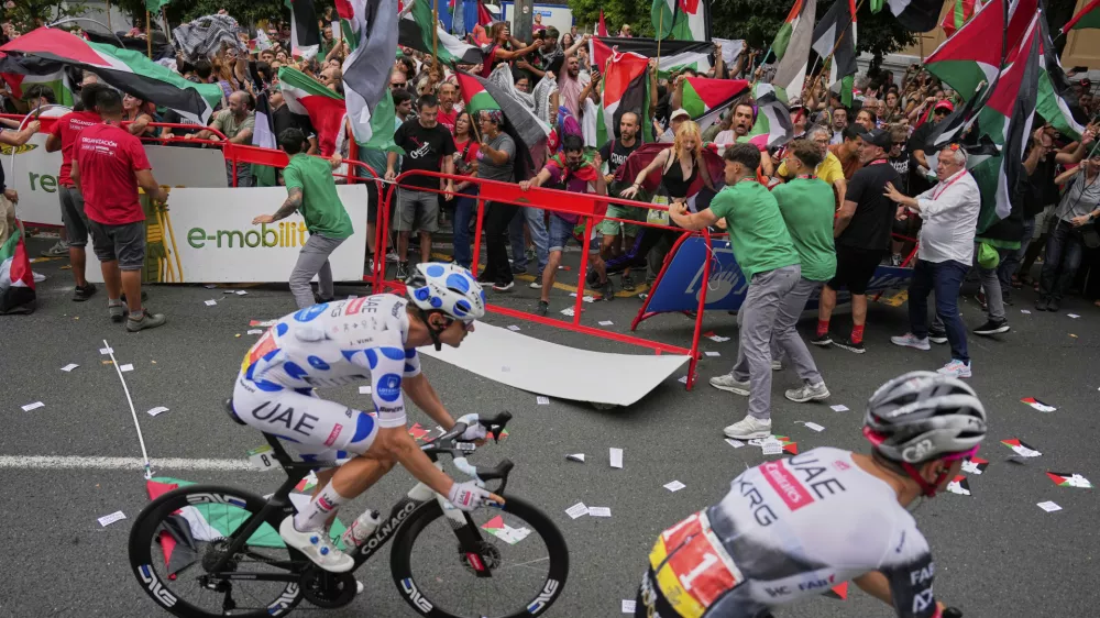 People hold Palestinian flags as they try to disrupt the eleventh stage of the Spanish Vuelta cycling race, from Bilbao to Bilbao, Spain, Wednesday, Aug. 3, 2025. (AP Photo/Miguel Oses)