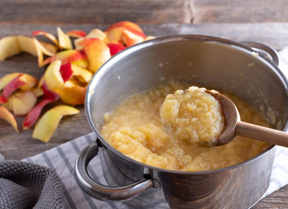 Traditional fresh cooked applesauce. Served in a saucepan and wooden spoon on rustic table. / Foto: Angelika Heine