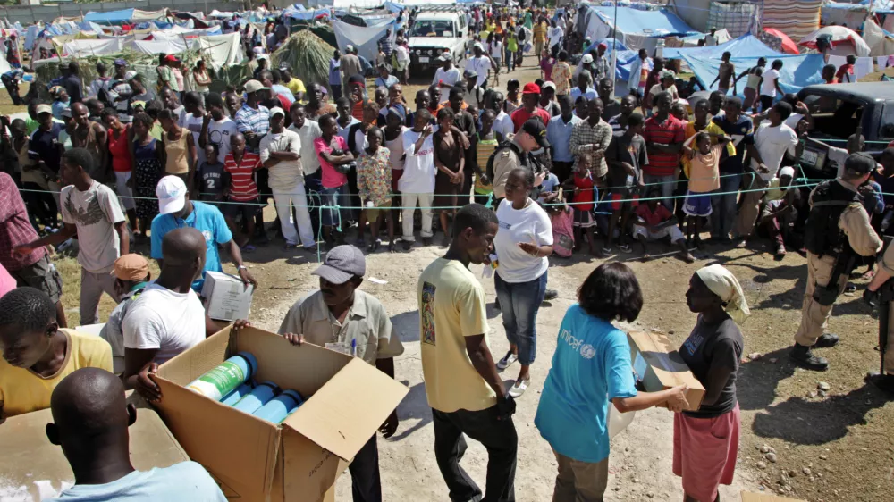 HAITI - On 24 January, Haitian aid workers and UNICEF and World Food Programme staff prepare to distribute relief supplies in the Pinchinat camp for people displaced by the earthquake, on a football pitch in the city of Jacmel. Supplies include bedding, water jugs, kitchen items and mosquito bed nets. Several UNICEF staff members wear T-shirts bearing the UNICEF logo. In a joint rapid response, UNICEF and the World Food Programme (WFP) are providing a daily hot meal for the estimated 5,000 people living in the camp. Assisted by MINUSTAH, the two agencies are also providing safe water in the camp. Some 34,000 people in Jacmel have been affected by the quake.On 24 January 2010 in Haiti, humanitarian assistance for survivors of the 7.3 magnitude earthquake that hit the country on 12 January continues to improve as capacity and logistical constraints are addressed. The quakes epicentre was only 17 kilometres from Port-au-Prince, the capital, and needs remain great. Quake aftershocks on 20 and 23 January caused further damage, especially in the town of Petit Goave. Unaccompanied children who have lost or been separated from their families are among the most vulnerable. Revised estimates by the Government report that more than 112,000 people were killed during the quake and 1.5 million have been left homeless. In Port-au-Prince, estimated numbers of people living in makeshift shelters range from 370,000800,000, despite the recent exodus of as many as 235,000 from the devastated city. Major government and private infrastructure have been destroyed or heavily damaged, including hospitals, water, sanitation and electrical systems, and telecommunications, banks and transportation networks. United Nations and UNICEF buildings and residences were also hit, and UN staff and peacekeepers with the UN Stabilization Mission in Haiti (MINUSTAH) are missing and more than 50 are confirmed to have died. MINUSTAH, totalling 7,000 peacekeepers and 2,000 police, have relocated their logistics base close to the airport to better coordinate incoming international relief assistance. The UN Consolidated Flash Appeal for the Haiti earthquake emergency requests US $575 million for relief and recovery for the next six months. UNICEFs portion of the appeal is US $127.9 million and UNICEF is the lead coordinating agency for education, child protection, nutrition and WASH (water, sanitation and hygiene). Working with the Government, other UN agencies, international and local NGOs and private partners, UNICEF is distributing safe water and equipment and health and shelter supplies, and establishing child feeding centres for children under age five. UNICEF is also working with partners to establish safe spaces for unaccompanied children and implementing procedures to identify, register and help reunite them with their families. Support has also been given to the Government to monitor children who are departing the country, to ensure that proper documentation and permissions are in place. This latest catastrophe exacerbates Haitis already critical humanitarian situation. An estimated 46 per cent of its nearly 10 million inhabitants are under age 18, and more than 78 per cent of the population lives on less than US $2.00 a day.