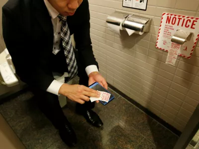 A man demonstrates a toilet roll for wiping smartphones, installed by Japanese mobile phone company NTT Docomo, in a high-tech bathroom equipped with bidet and heated seat at Narita international airport in Narita, Japan, December 28, 2016. REUTERS/Toru Hanai