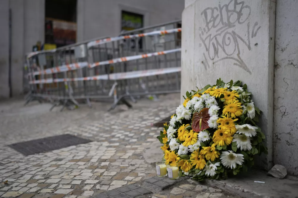 Flowers are photographed at the site where a tourist streetcar derailed and crashed in Lisbon, Portugal, Friday, Sept. 5, 2025. (AP Photo/Armando Franca)
