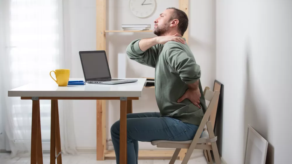 Man with neck pain while working on a laptop. / Foto: M-gucci