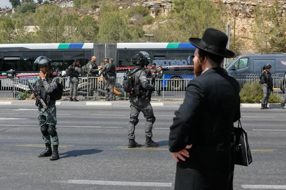 A man stands as Israeli security personnel secure the scene where a suspected shooting attack took place at the outskirts of Jerusalem, September 8, 2025 REUTERS/Ammar Awad