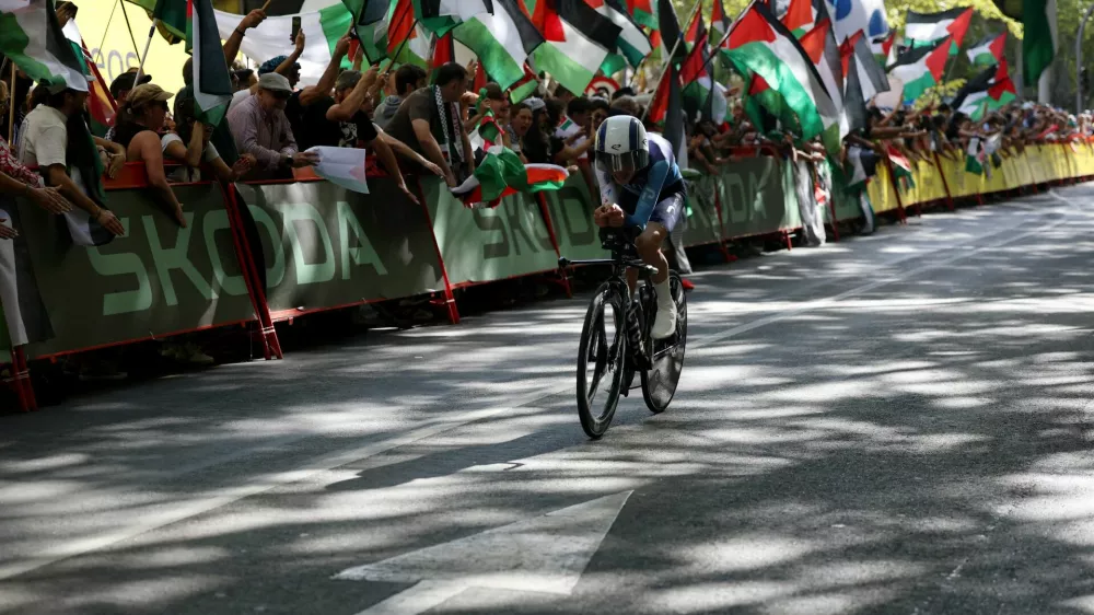 Cycling - Vuelta a Espana - Stage 18 - Valladolid to Valladolid - Valladolid, Spain - September 11, 2025 Israel - Premier Tech's Pier-Andre Cote in action as pro-Palestine protestors are pictured in the background REUTERS/Juan Medina