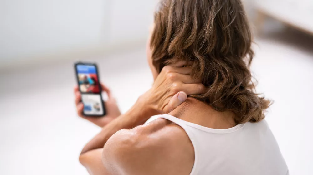 Woman With Neck Pain Sitting Using Mobile Phone