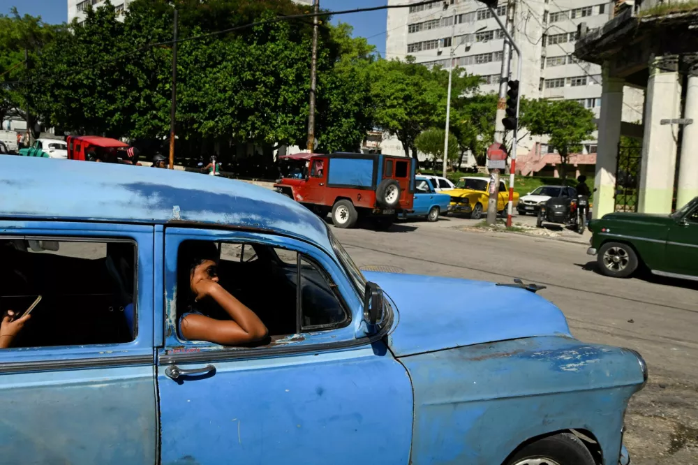 People ride in a classic car during a national power grid collapse, for the fourth time in less than a year, which caused a nationwide blackout, in Havana, Cuba, September 10, 2025. REUTERS/Norlys Perez