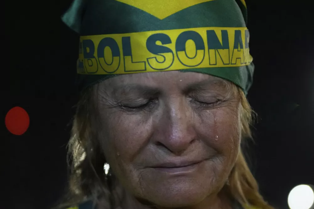 A supporter of former President Jair Bolsonaro cries during a vigil in his support near his home where he is under house arrest in Brasilia, Brazil, Thursday, Sept. 11, 2025. (AP Photo/Eraldo Peres)