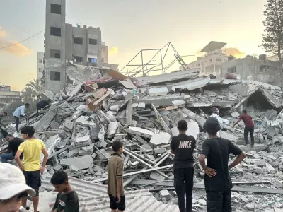 15 September 2025, Palestinian Territories, Gaza: People gather outside a building damaged in an Israeli airstrike west of Gaza City. Photo: Hasan Alzaanin/TASS via ZUMA Press/dpa