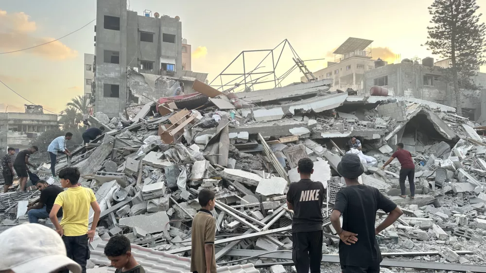 15 September 2025, Palestinian Territories, Gaza: People gather outside a building damaged in an Israeli airstrike west of Gaza City. Photo: Hasan Alzaanin/TASS via ZUMA Press/dpa