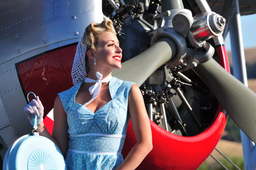 closeup of a classic 1940's lady in front of a vintage biplane