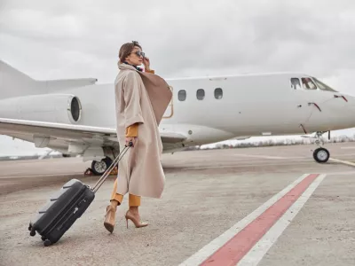 Mature business woman in coat near her jet in airport