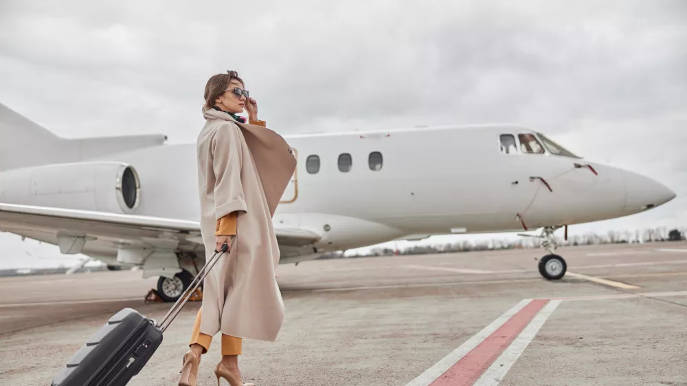 Mature business woman in coat near her jet in airport