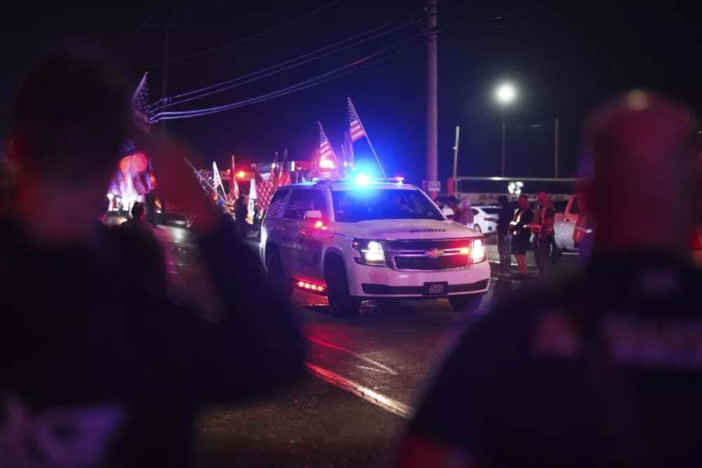 People salute as a York County sheriff vehicle drives past during a procession Wednesday, Sept. 17, 2025, in Spring Grove, Pa., after multiple police officers were shot and killed. (AP Photo/Matt Slocum)