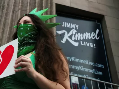 A woman wears a Statue of Liberty costume as she holds an image of a broken heart, outside the El Capitan Entertainment Centre, where "Jimmy Kimmel Live!" is recorded for broadcast, on Hollywood Boulevard in Los Angeles, California, U.S. September 17, 2025. REUTERS/Daniel Cole   TPX IMAGES OF THE DAY