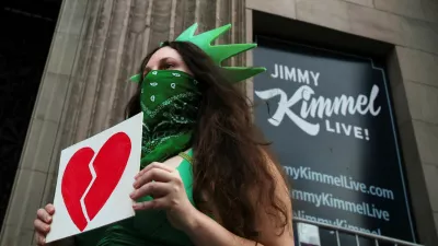 A woman wears a Statue of Liberty costume as she holds an image of a broken heart, outside the El Capitan Entertainment Centre, where "Jimmy Kimmel Live!" is recorded for broadcast, on Hollywood Boulevard in Los Angeles, California, U.S. September 17, 2025. REUTERS/Daniel Cole   TPX IMAGES OF THE DAY