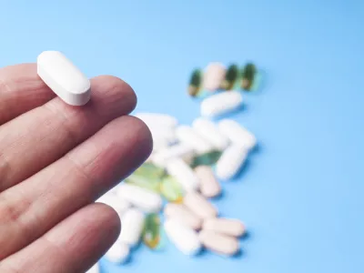 Medicine pills or capsules in hand, palm or fingers. Many pills and tablets. Pharmaceutical medicament, cure in container for health. Antibiotic, painkiller closeup.Many pills and tablets isolated on light blue background. Pharmaceutical medicament, cure in container for health. Antibiotic, painkiller and thermometer closeup.Many pills and tablets isolated on light blue background. Pharmaceutical medicament, cure in container for health. Antibiotic, painkiller and thermometer closeup.