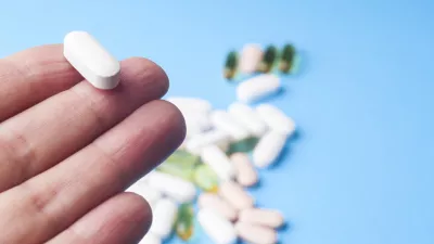 Medicine pills or capsules in hand, palm or fingers. Many pills and tablets. Pharmaceutical medicament, cure in container for health. Antibiotic, painkiller closeup.Many pills and tablets isolated on light blue background. Pharmaceutical medicament, cure in container for health. Antibiotic, painkiller and thermometer closeup.Many pills and tablets isolated on light blue background. Pharmaceutical medicament, cure in container for health. Antibiotic, painkiller and thermometer closeup.