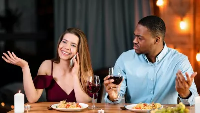 Annoyed African Man Looking At His Girlfriend Talking On Mobile Phone During Romantic Dinner In Restaurant, Complaining About Her Cellphone Addiction. Interracial Couple Having Communication Problems,Image: 1017031699, License: Royalty-free, Restrictions:, Model Release: no