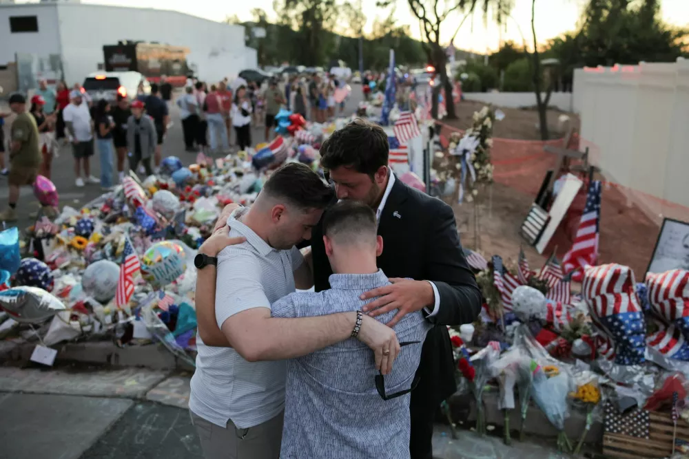 People pray next to a tribute for slain conservative commentator Charlie Kirk at the headquarters of Turning Point USA, ahead of a memorial service for him which is to be held on September 21, in Phoenix, Arizona, U.S., September 20, 2025. REUTERS/Daniel Cole
