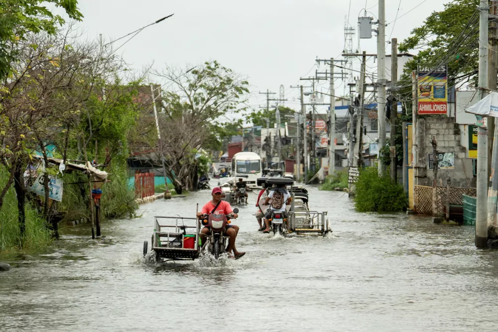 Motorists wade through a flooded road, following heavy rains intensified by Super Typhoon Ragasa, in Apalit, Pampanga province, Philippines, September 23, 2025. REUTERS/Lisa Marie David