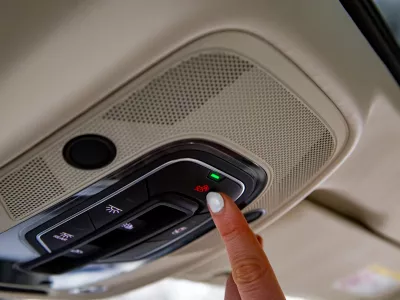 female driver's finger presses sos button on the ceiling panel of a modern car / Foto: Maria Argutinskaya