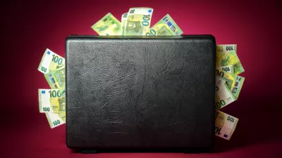A briefcase overflowing with euro banknotes. Concept studio shot on illuminated burgundy red background with dark vignette / Foto: Smileus