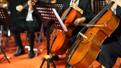 Hands playing cello orchestra with note sheet on stage. / Foto: Yori Meirizan