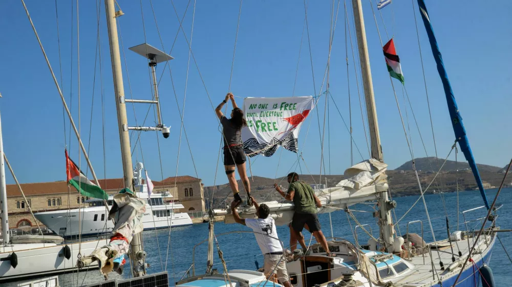 People hang a banner before the departure of the sailing boats Electra and Oxygen, part of the Global Sumud Flotilla, from the port of Ermoupolis on Syros island, Greece, September 14, 2025. REUTERS/Giorgos Solaris