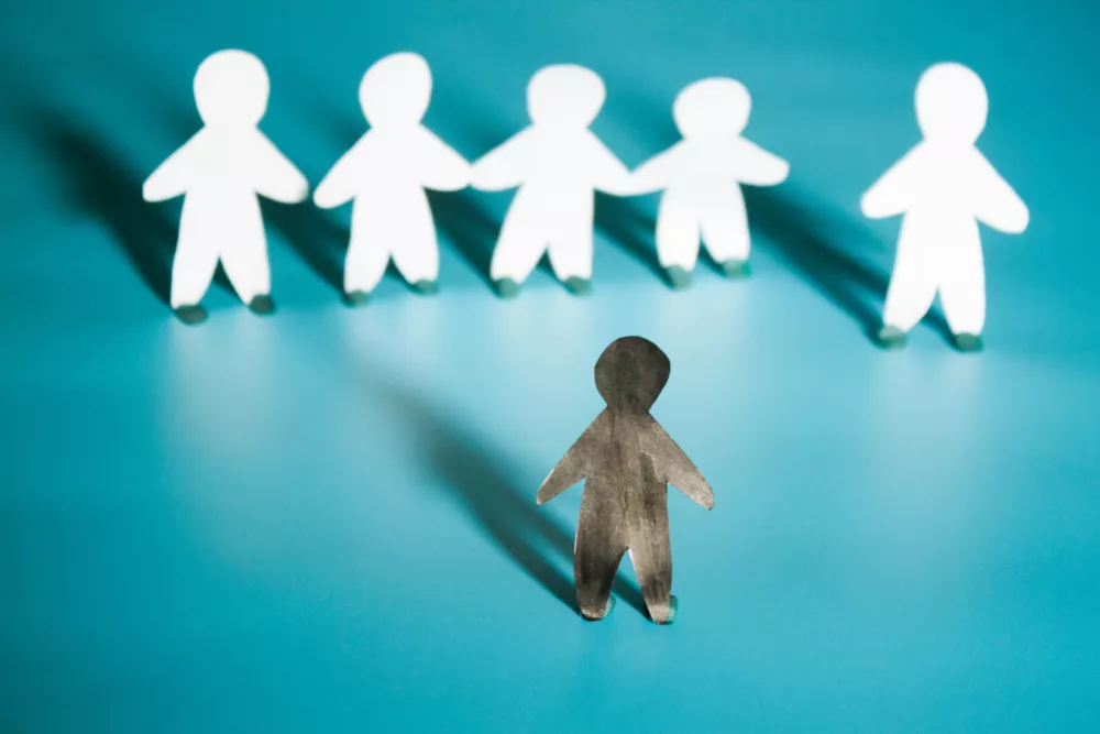 Racism concept image. White paper person agains black paper person / Foto: Liia Galimzianova