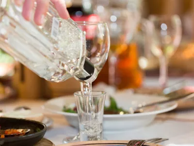 Feast in a restaurant, pouring vodka into the glass closeup