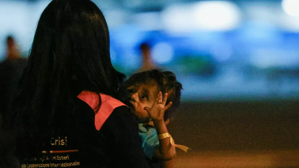 A person holds a Palestinian child who was evacuated from Gaza via a humanitarian airlift and arrived in Italy with relatives for medical treatment, at Ciampino Military Airport in Ciampino, Italy September 29, 2025. REUTERS/Francesco Fotia