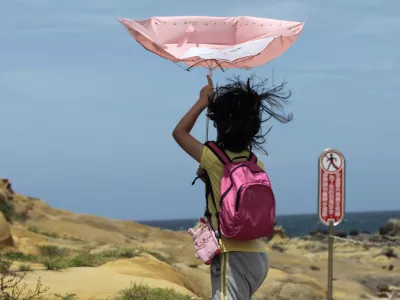 A girl struggles with winds from approaching Typhoon Matmo along the eastern coast of Keelung, northeastern Taiwan, Tuesday, July 22, 2014. The eye of Typhoon Matmo is expected to make landfall in eastern Taiwan early Wednesday bringing heavy rain and winds with gusts over 130 kilometers (85 miles) per hour. (AP Photo/Wally Santana)