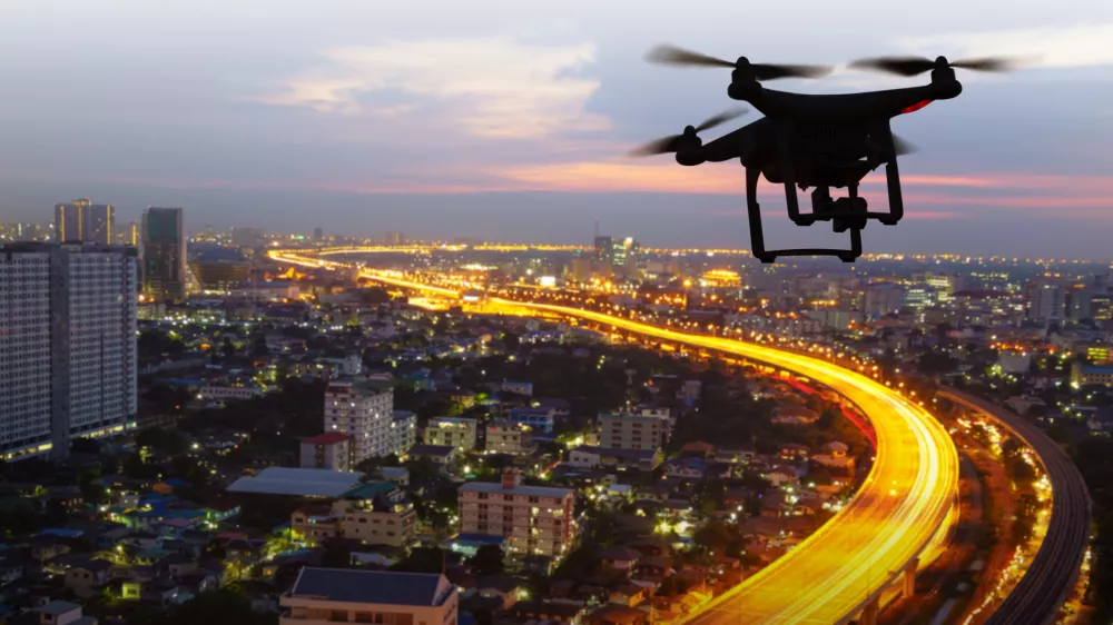 Silhouette of drone flying above city at sunset / Foto: Naypong