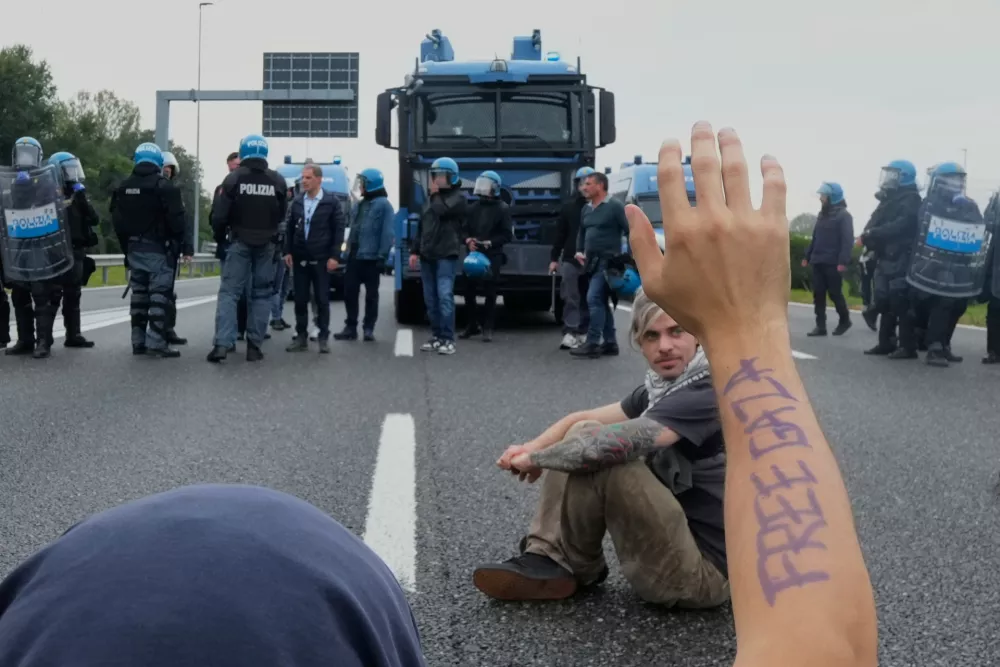 Pro-Palestinian demonstrators sits on the Milan's ring road during a protest part of a national general strike called by different unions to protest against the situation in Gaza two days after Israeli forces intercepted a Gaza-bound aid flotilla in the Mediterranean Sea, in Milan, Italy, Friday, Oct. 3, 2025. (AP Photo/Luca Bruno)