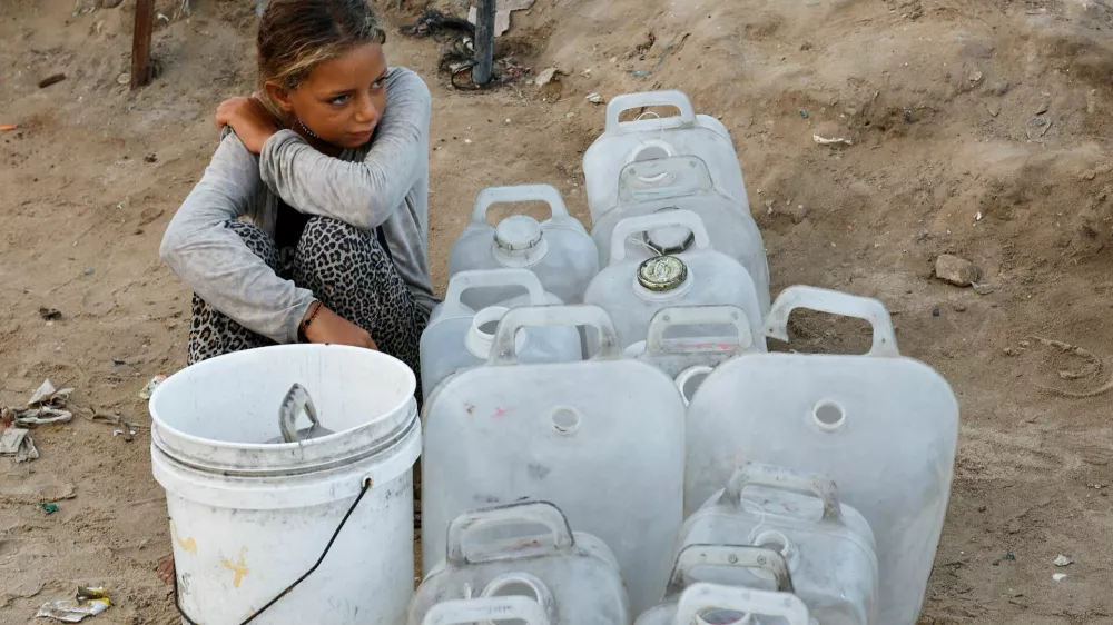 A displaced Palestinian girl waits to collect water after Hamas agreed to release hostages and accept some other terms in a U.S. plan to end the war, in the central Gaza Strip October 4, 2025. REUTERS/Mahmoud Issa