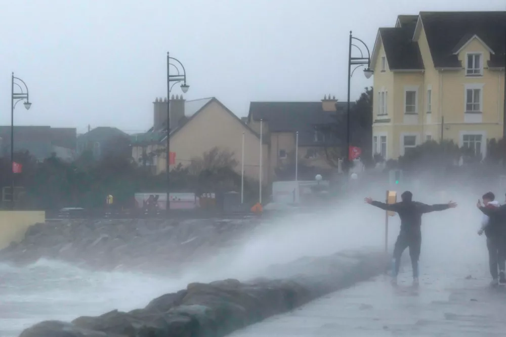 People stand in front of waves during Storm Amy which brought severe weather, in Galway, Ireland, October 3, 2025. REUTERS/Clodagh Kilcoyne