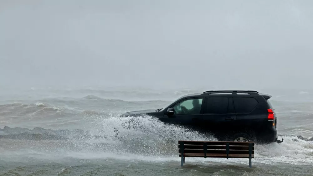 A car drives through a flooded park next to the sea during Storm Amy which brought severe weather, in Galway, Ireland, October 3, 2025. REUTERS/Clodagh Kilcoyne