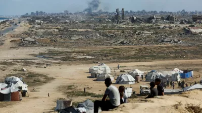 Palestinians look on as smoke rises following explosions in Gaza City, as seen from central Gaza Strip October 5, 2025. REUTERS/Mahmoud Issa