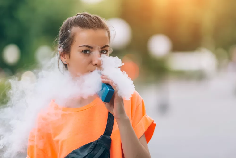Pretty young girl vape popular ecig gadget,vaping device.Happy brunette vaper girl with e-cig.Portrait of smoker female model with electronic cigarette vaporizer.Ejuice vaping with fruit flavor liquid