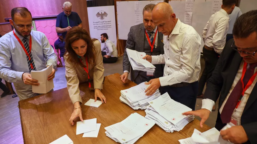 Officials count the votes of electoral college members in a parliamentary election at a polling station in Aleppo, Syria, Sunday, Oct. 5, 2025. (AP Photo/Omar Albam)