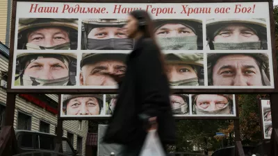 A woman walks past a gallery of portraits of Russian service members involved in the country's military campaign in Ukraine, that is placed in a street near the office of a charity fund collecting donations on vehicles for the use of Russia's army during a conflict against Ukraine, in Saint Petersburg, Russia, October 6, 2025. A slogan on the board reads: "Our dear ones. Our heroes. God bless you!" REUTERS/Anton Vaganov