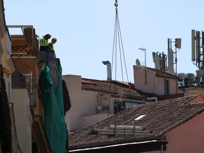 Workers stand on a building at the site of a collapse in central Madrid, Spain, October 7, 2025. REUTERS/Juan Medina