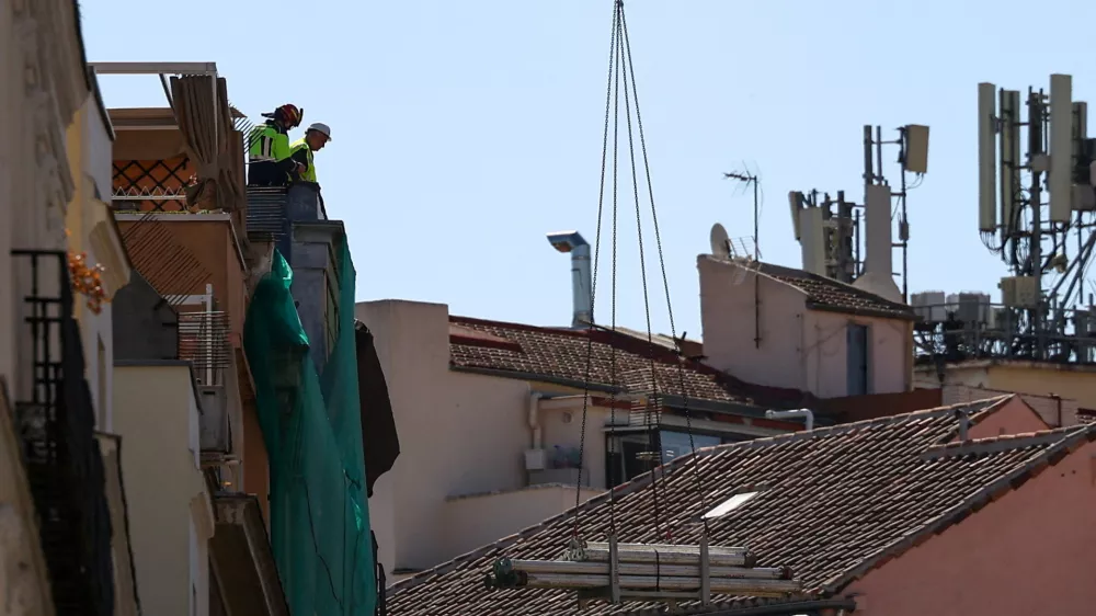 Workers stand on a building at the site of a collapse in central Madrid, Spain, October 7, 2025. REUTERS/Juan Medina