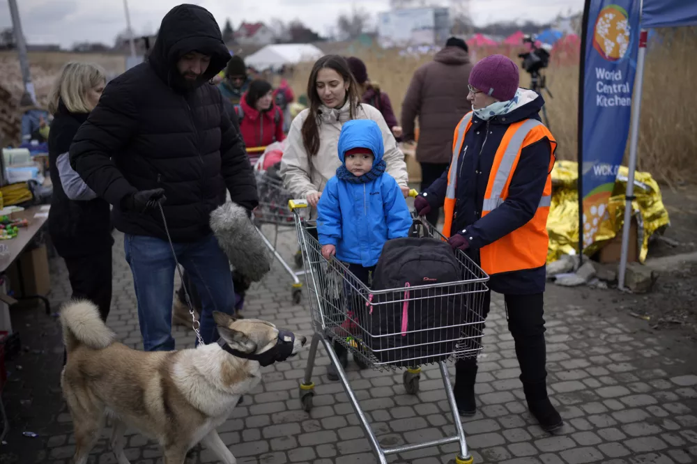 Refugees are assisted by a volunteer after crossing from Ukraine in Medyka, Poland, Wednesday, March 9, 2022. (AP Photo/Daniel Cole)