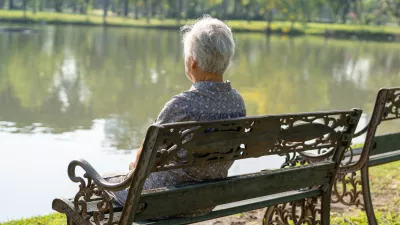 Asian elderly woman depressed and sad sitting back on bench in autumn park.