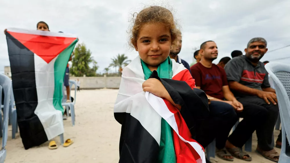 A girl holds a Palestinian flag, after U.S. President Donald Trump announced that Israel and Hamas agreed on the first phase of a Gaza ceasefire, in the central Gaza Strip October 9, 2025. REUTERS/Mahmoud Issa   TPX IMAGES OF THE DAY