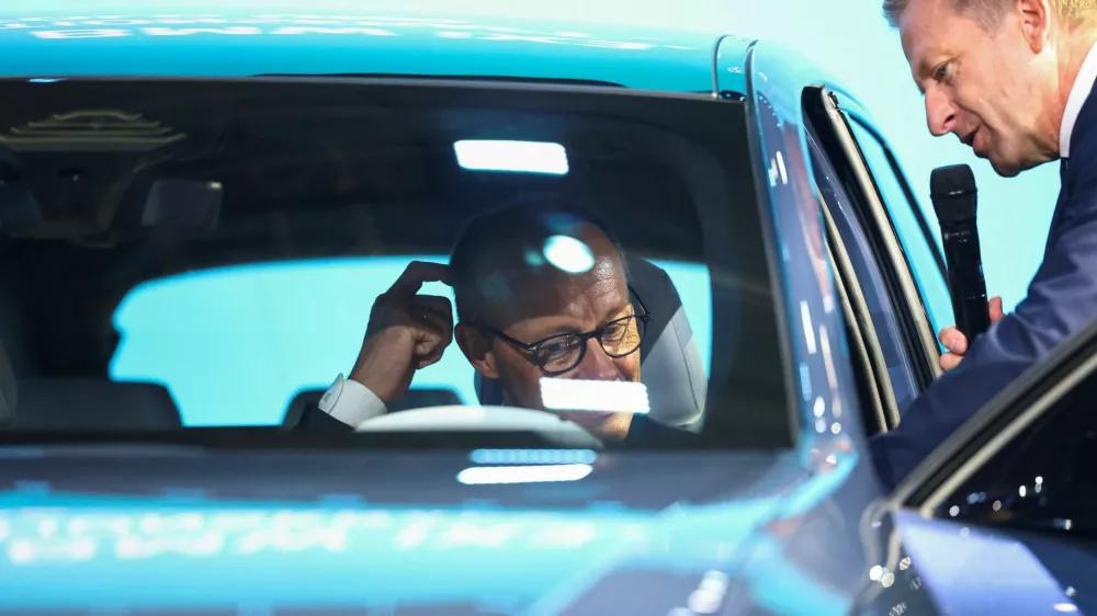 German Chancellor Friedrich Merz gestures as BMW Group CEO Oliver Zipse shows him a BMW iX3 at the IAA Mobility 2025 auto show in Munich, Germany, September 9, 2025. REUTERS/Kai Pfaffenbach
