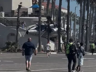People and emergency personnel walk next to a helicopter wreckage lying on a structure following a crash in Huntington Beach, California, U.S., October 11, 2025, in this screengrab obtained from social media video. Tim Robinson/via REUTERS THIS IMAGE HAS BEEN SUPPLIED BY A THIRD PARTY. MANDATORY CREDIT. NO RESALES. NO ARCHIVES. VERIFICATION - Reuters was able to independently verify the location of the video by building exterior, structures and trees matched file images. - Reuters was able to verify the date of the footage from the original file metadata.
