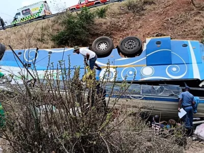 In this photo made available by the South African Department of Transport and Community Safety, Police officers and emergency rescue workers search for victims from a bus lying upside down in the embankment, in Louis Trichardt, South Africa, Sunday, Oct. 12, 2025. (South African Department of Transport and Community Safety via AP)
