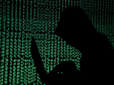 A hooded man holds a laptop computer as cyber code is projected on him in this illustration picture taken on May 13, 2017. Capitalizing on spying tools believed to have been developed by the U.S. National Security Agency, hackers staged a cyber assault with a self-spreading malware that has infected tens of thousands of computers in nearly 100 countries. REUTERS/Kacper Pempel/Illustration